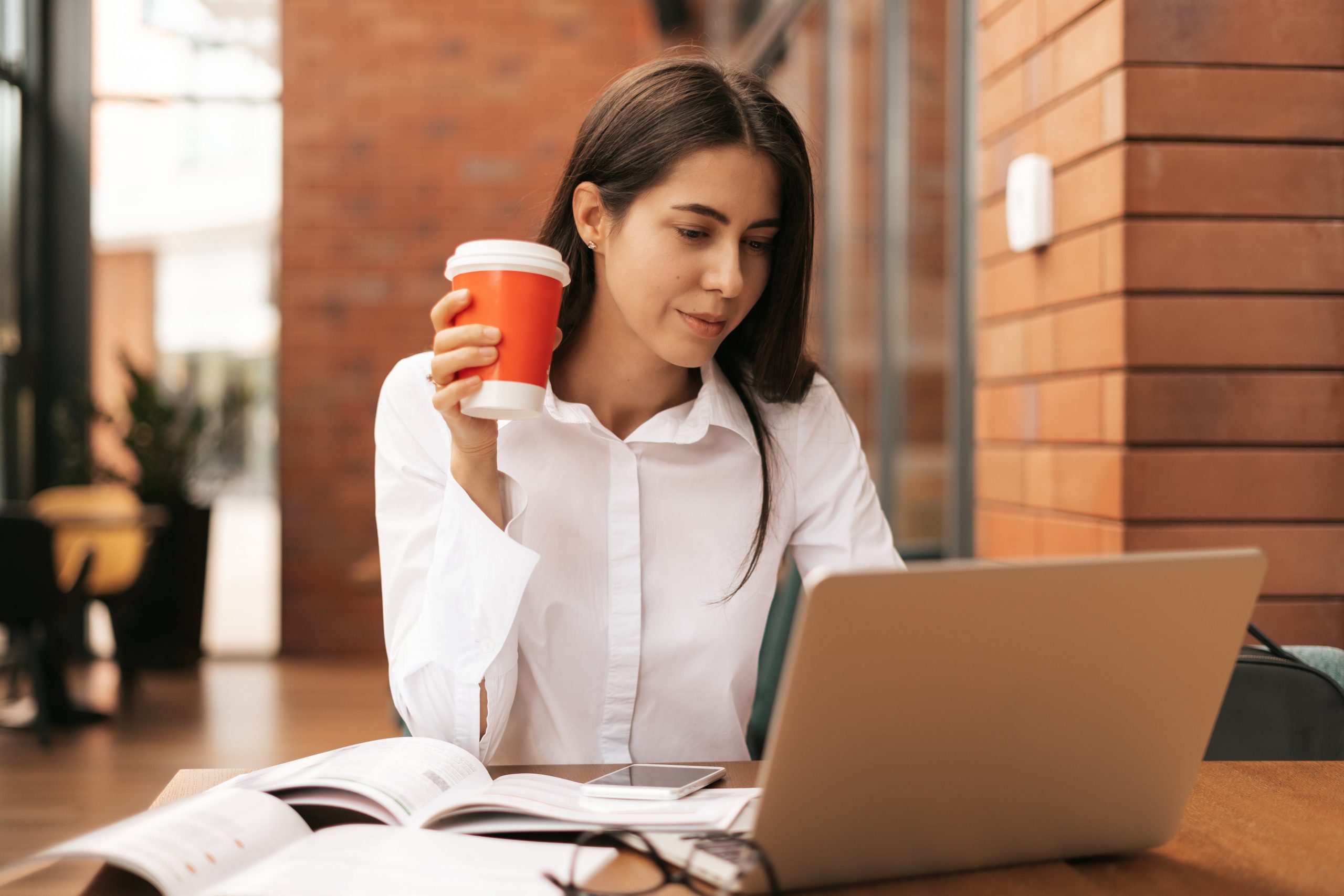 brunette-woman-drinking-coffee-to-go-while-working-2022-01-18-23-32-14-utc-min